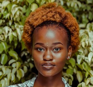 A woman named Olivia Ava with a stylish afro hairstyle, radiating confidence and charm